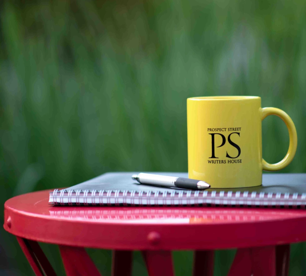 Red table with notebook, pen and coffee mug on top