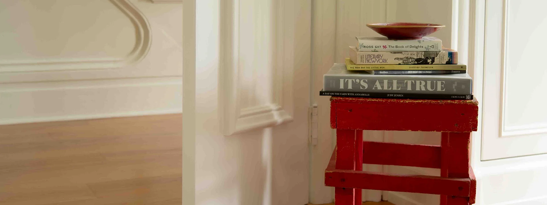 photo of stack of books on wooden stand in hallway