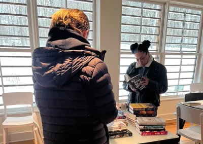 Two guests looking at books on table inside Prospect Street