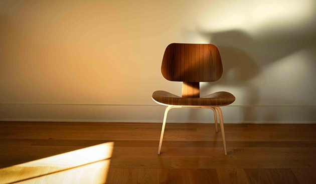 Empty chair in room with sun cast on floor