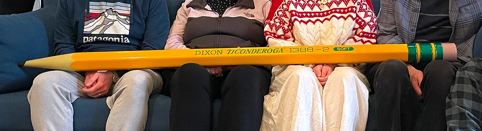 photo of group sitting on couch with large pencil across their laps