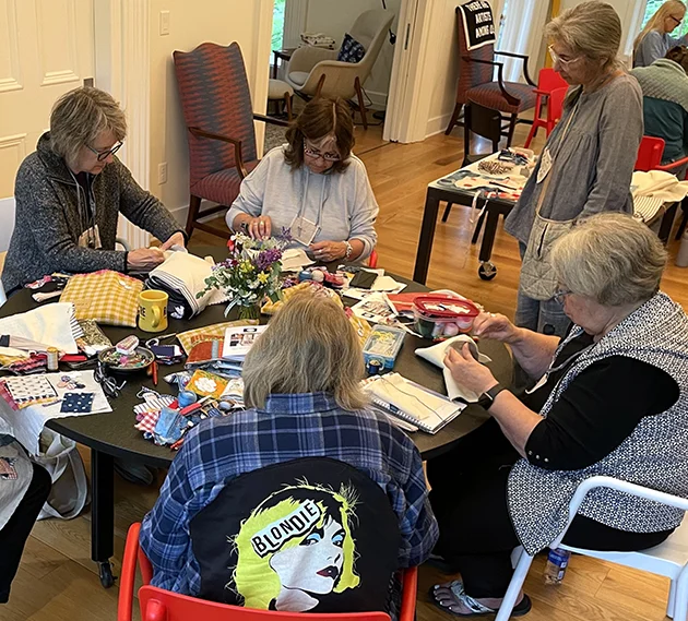Group of women sitting at table during stitching workshop