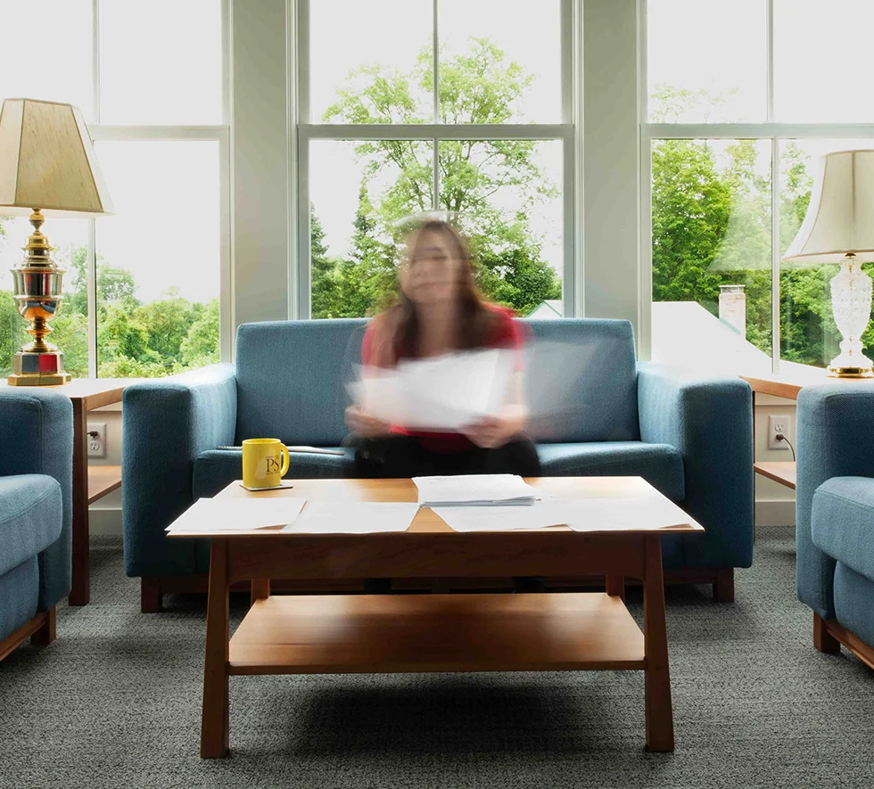 Woman sitting on couch in suite room shuffling through papers