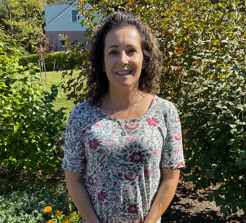 Rachel posing in front of bushes with house in background